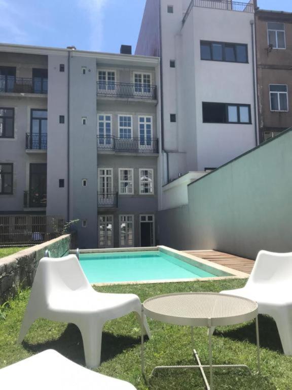 a swimming pool with two chairs and a table and two buildings at MyStay Porto - Urban Collection in Porto
