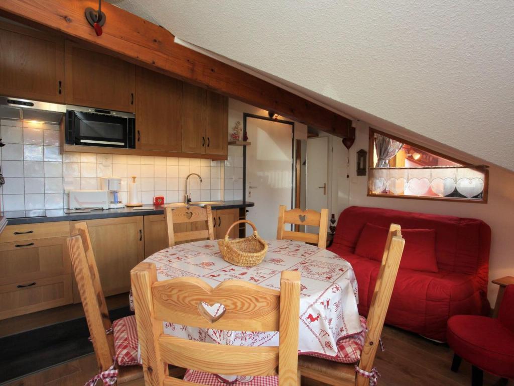une cuisine avec une table et un canapé rouge dans l'établissement Charmant Appartement Rénové pour 4 Pers avec Balcon Sud près des Pistes et Commerces - FR-1-417-67, à La Toussuire