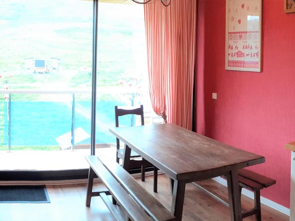 une table et des chaises dans une pièce avec une grande fenêtre dans l'établissement Charmant appart 4 pers avec balcon et parking au cœur de la station - FR-1-417-145, à La Toussuire