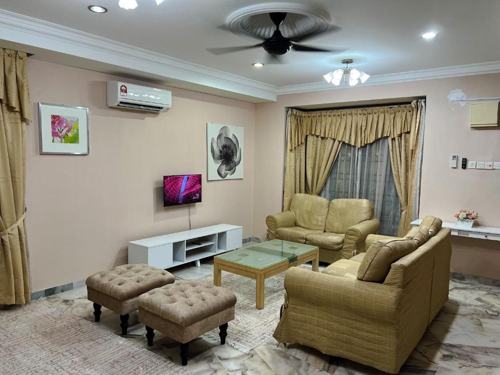 ein Wohnzimmer mit einem Sofa, Stühlen und einem TV in der Unterkunft D’Lestari Homestay in Seri Kembangan