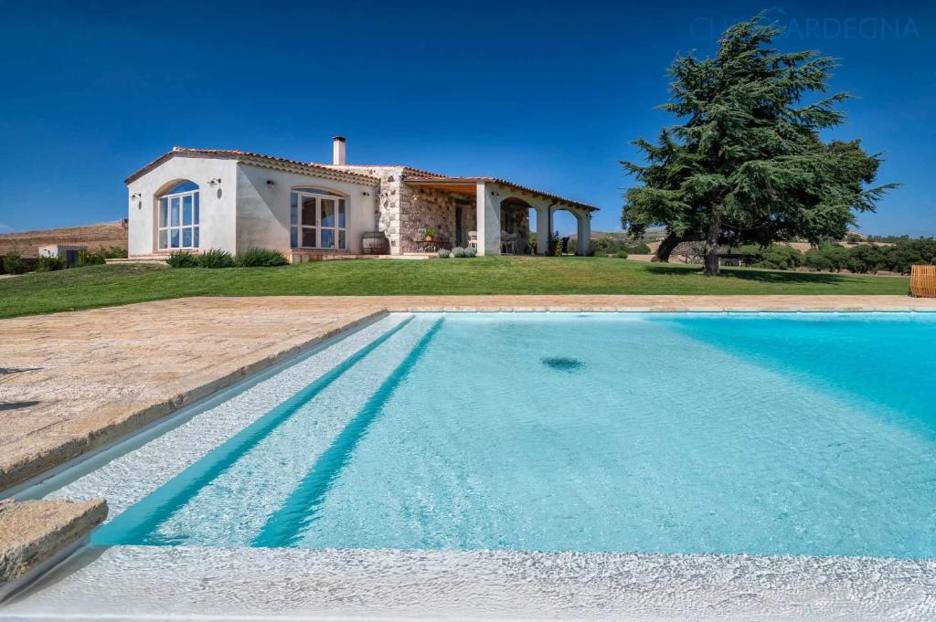 Villa con piscina frente a una casa en Tenute Shardana Luxury Farmhouse with SPA, Sauna, Heated Swimming Pool en Mores