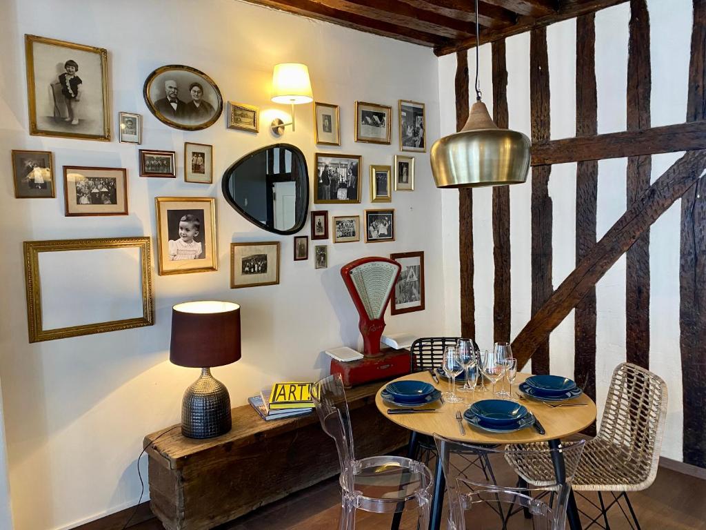 a dining room with a table with chairs and pictures on the wall at Le repaire d'Esmeralda in Orléans