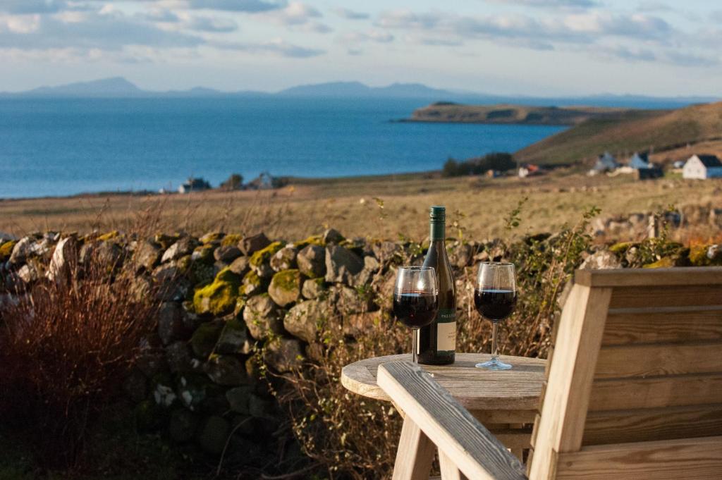 a table with two glasses of wine and a bottle at An Cala Beag Self Catering apartment on The Waternish Peninsula in Hallin