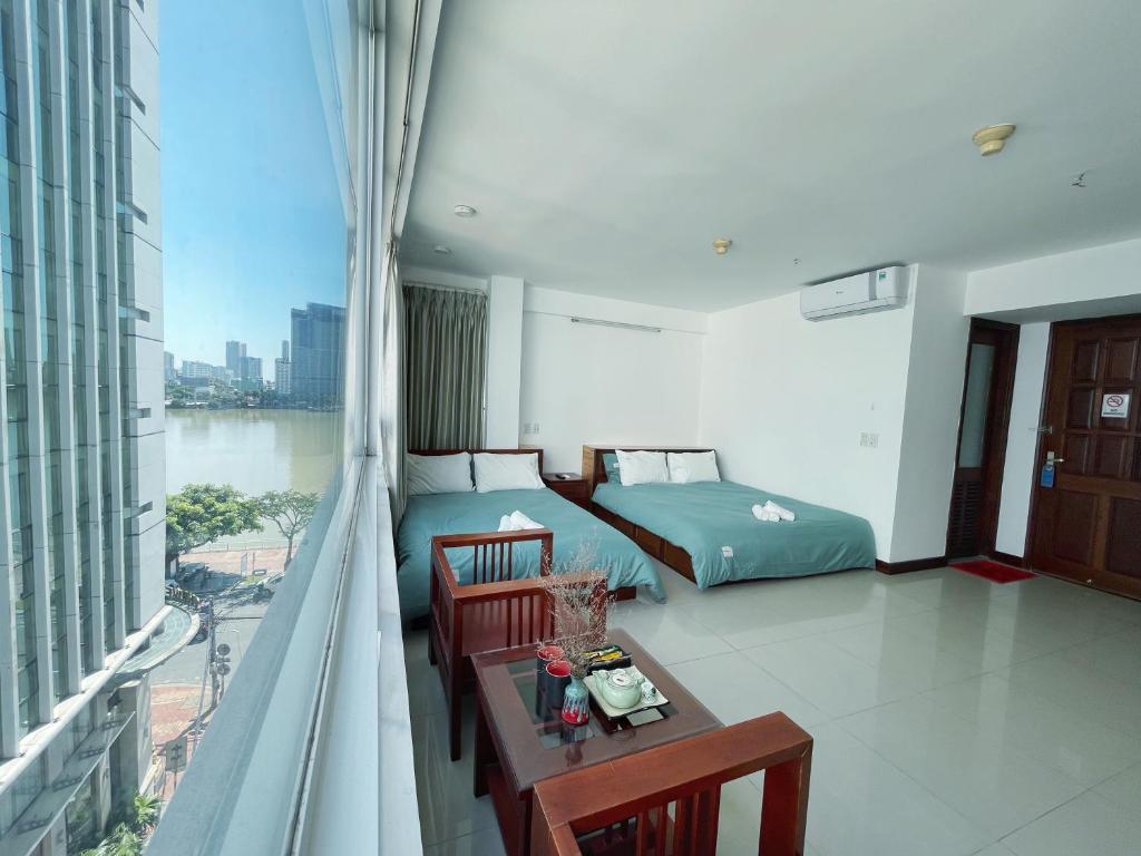 una camera da letto con balcone, letto e tavolo di Onestar Danang Riverside a Da Nang