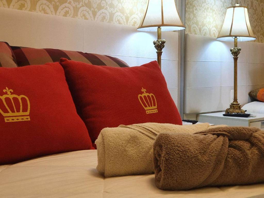 Cama con almohadas rojas y cojines de oro en Ape St Petrus Centro Gramado, en Gramado
