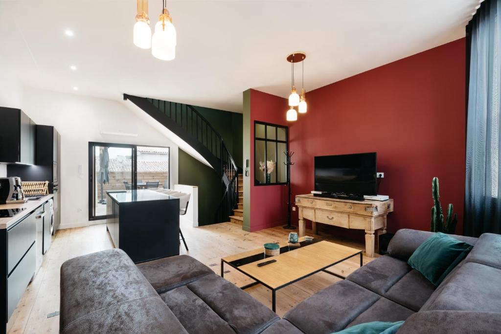 een woonkamer met een bank en een rode muur bij Avenue Ferry in Libourne