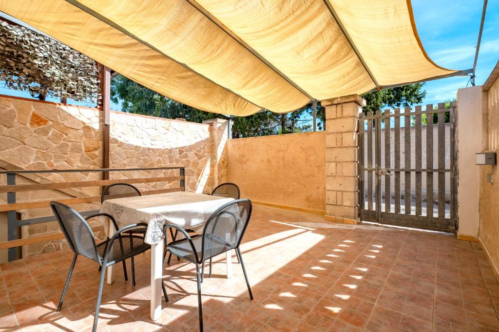 een patio met een tafel en stoelen en een hek bij Appartamento Acquadolce in Torre Ovo