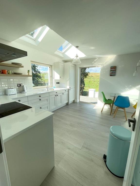 a large kitchen with white cabinets and a blue chair at Kathleen's Carrowkeel Cottage in Sligo