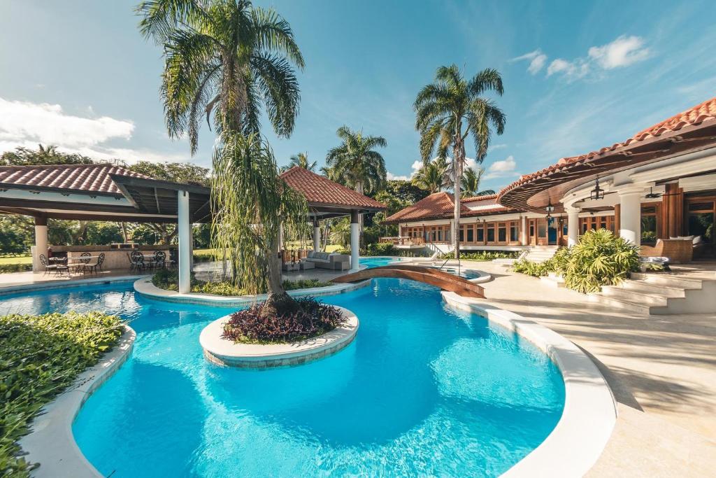 a pool with a palm tree in front of a building at Maison Larimar-Walking Distance to the Marina at Casa de Campo in La Romana