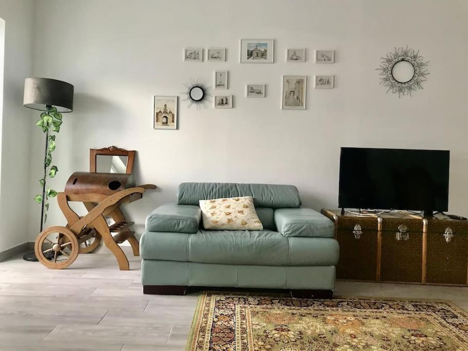 a living room with a green couch and a flat screen tv at Casa do Reguengo 1 in Estremoz