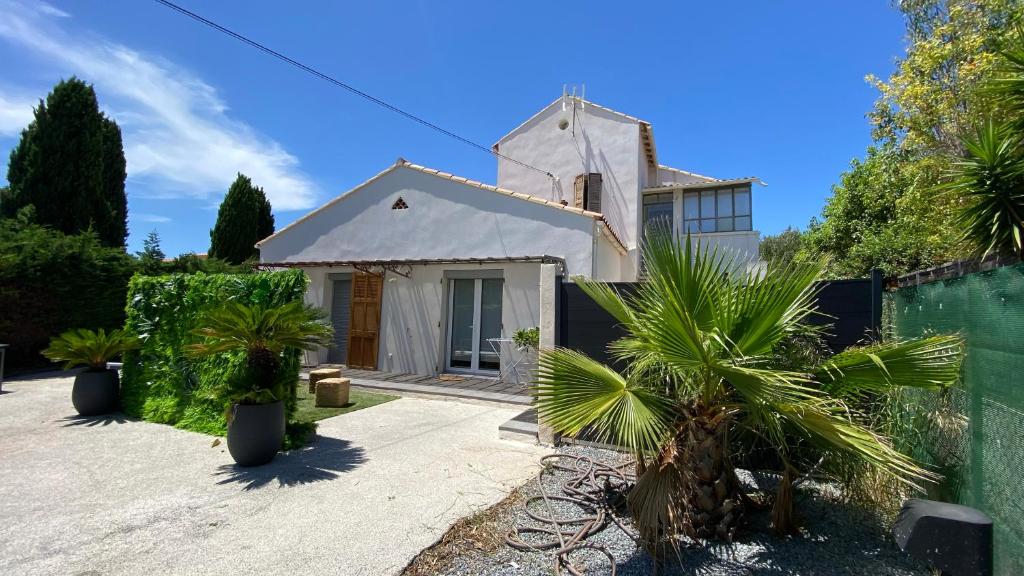 a white house with a fence and palm trees at Villa Pierre et Mer, maison 6 personnes a deux pas des plages in Hyères