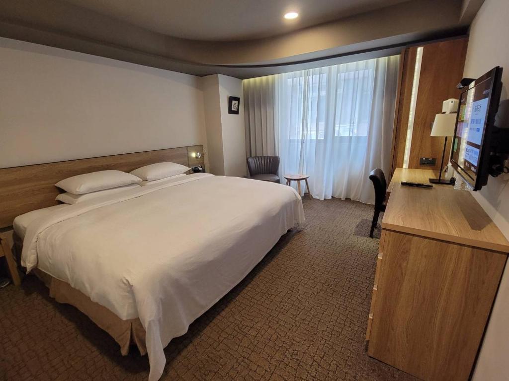 a hotel room with a large bed and a television at Simple + Hotel in Taipei