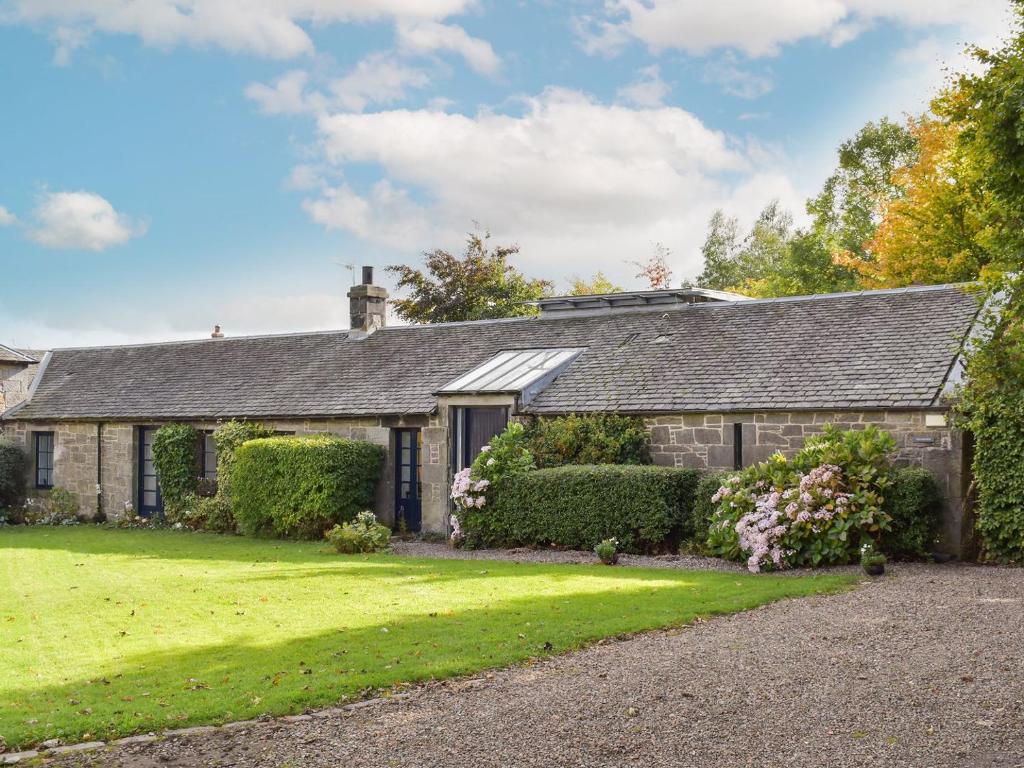 an old stone house with a green yard at Tigh Nam Muc in Loanhead