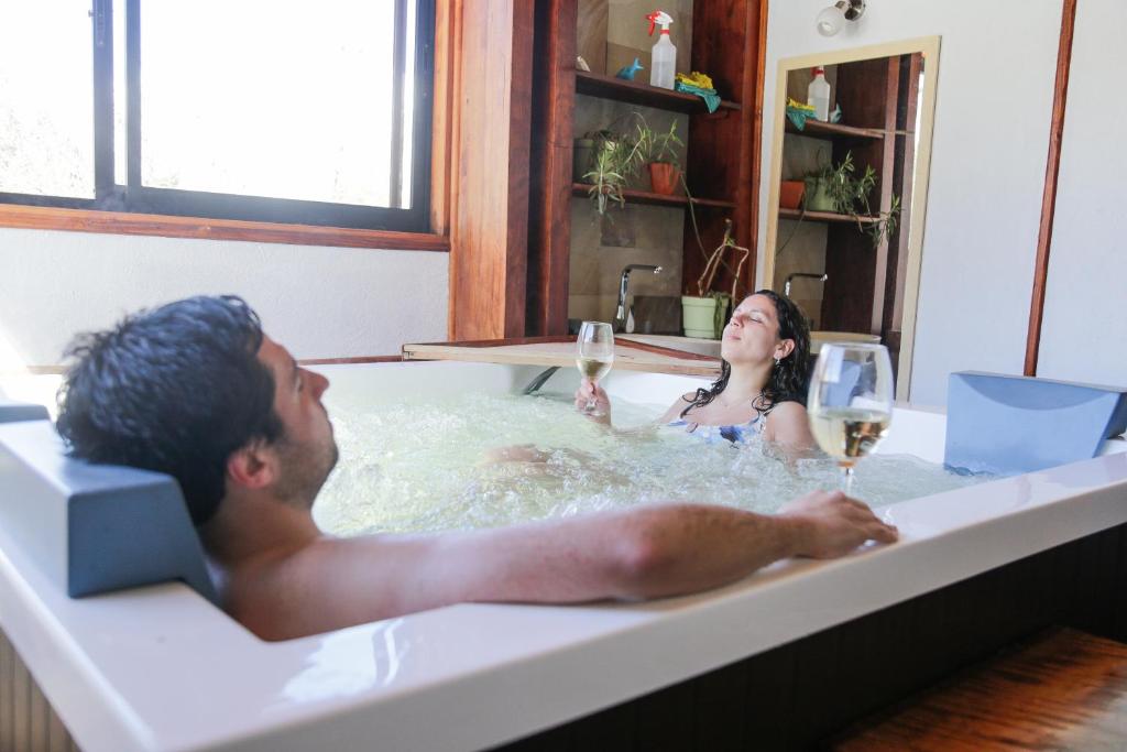 a man and woman in a bathtub with wine glasses at MI Lodge Las Trancas Hotel & Spa in Las Trancas
