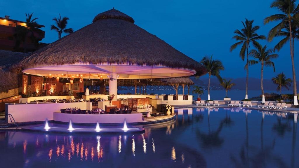 un complejo con piscina y bar por la noche en Beachfront Resort Condo beside la Isla Mall en Puerto Vallarta