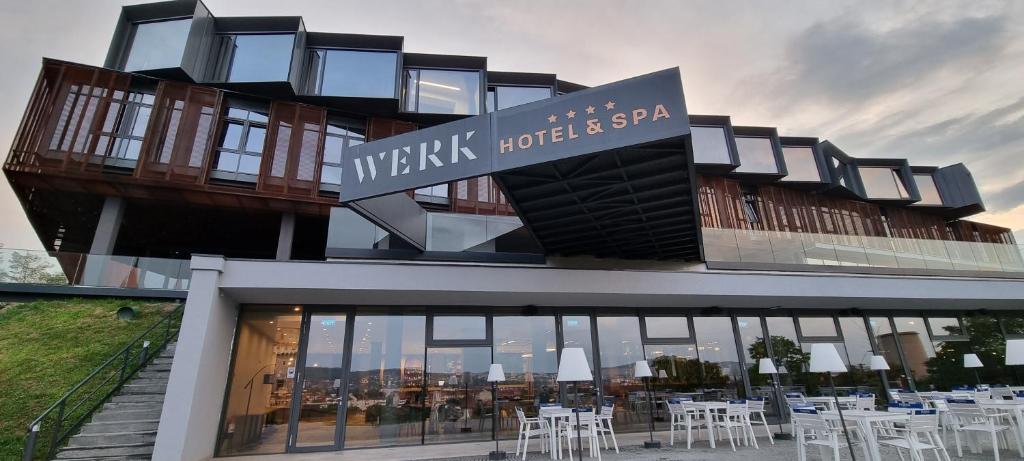 WERK Hotel & SPA في هونيدوارا: مبنى عليه طاولات وكراسي بيضاء