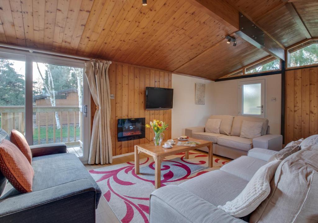 ein Wohnzimmer mit einem Sofa und einem Tisch in der Unterkunft Birch Lodge in Thornton Watlass