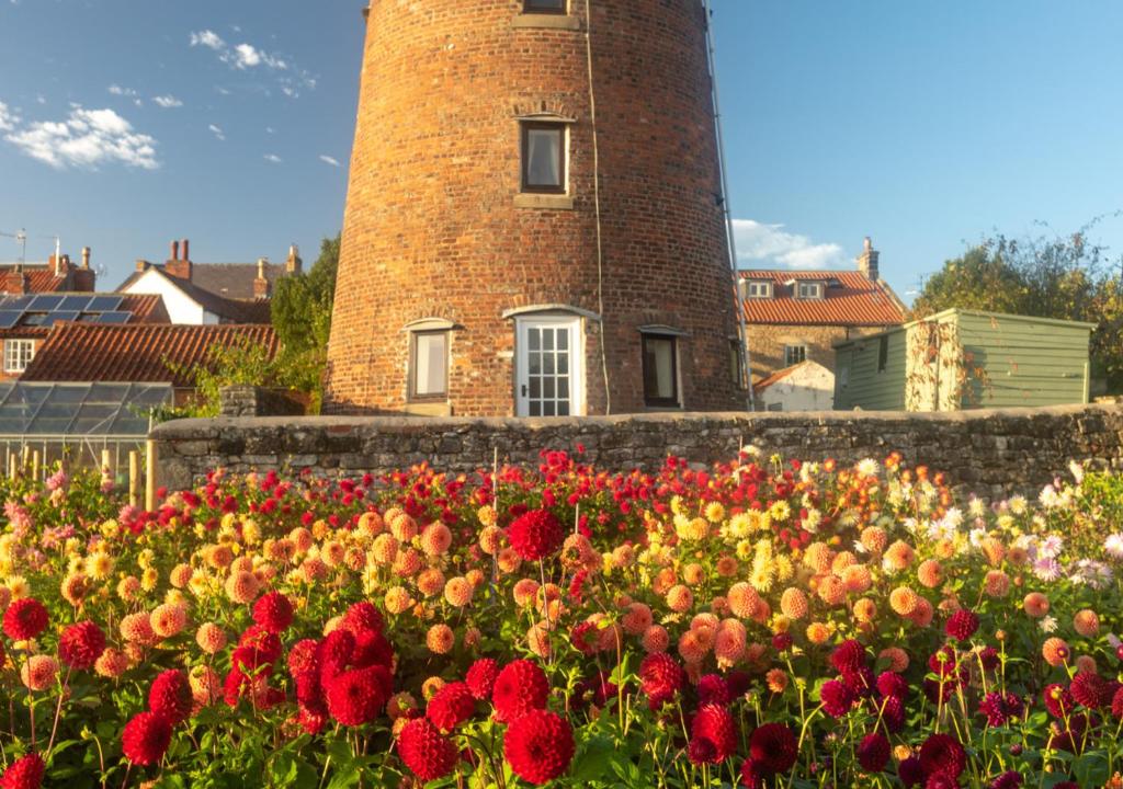 a field of flowers in front of a brick tower at The Old Windmill in Kirkbymoorside