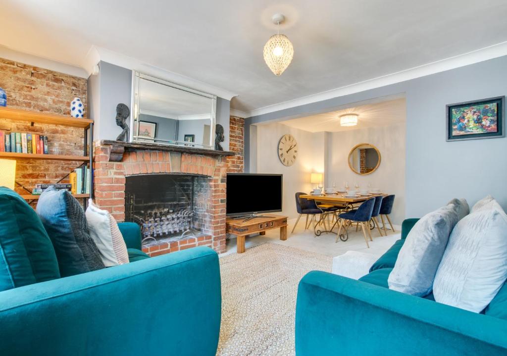 a living room with two blue couches and a fireplace at Pebble Beach Cottage in Rottingdean
