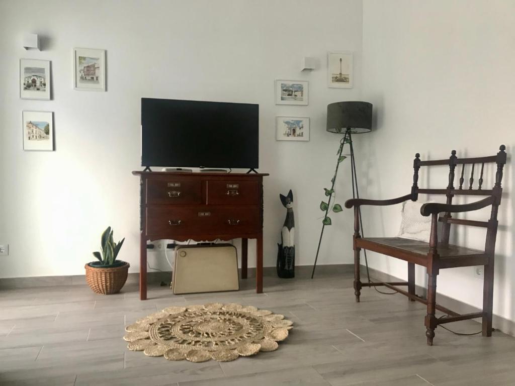 uma sala de estar com uma televisão de ecrã plano e uma cadeira em Casa do Reguengo 2 em Estremoz