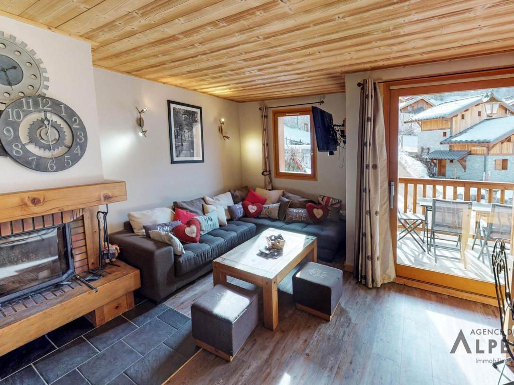 een woonkamer met een bank en een open haard bij Chalet haut de gamme 8 chambres avec sauna à 250m des pistes, St Martin de Belleville - FR-1-452-75 in Saint-Martin-de-Belleville