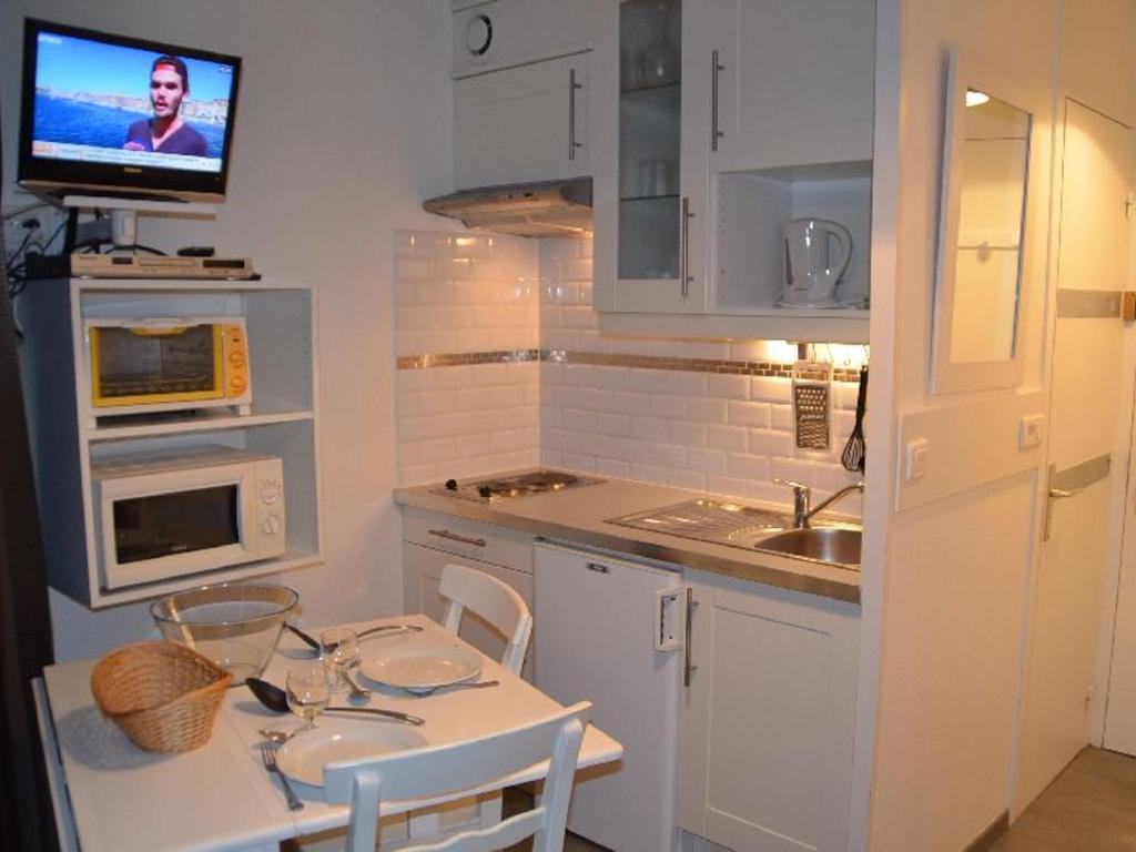 uma pequena cozinha com uma mesa e uma televisão na parede em Studio Les Menuires, 1 pièce, 2 personnes - FR-1-452-87 em Les Menuires
