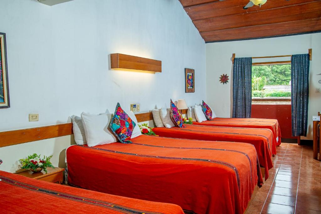 a row of four beds in a room at Hotel Panchoy by AHS in Antigua Guatemala