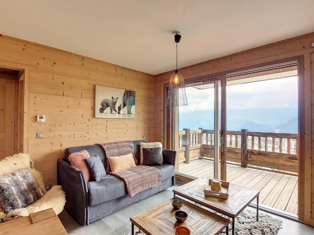 un salon avec un canapé et une grande fenêtre dans l'établissement Bel appartement sur les pistes avec parking, balcon et équipements modernes - FR-1-416-190, à La Toussuire