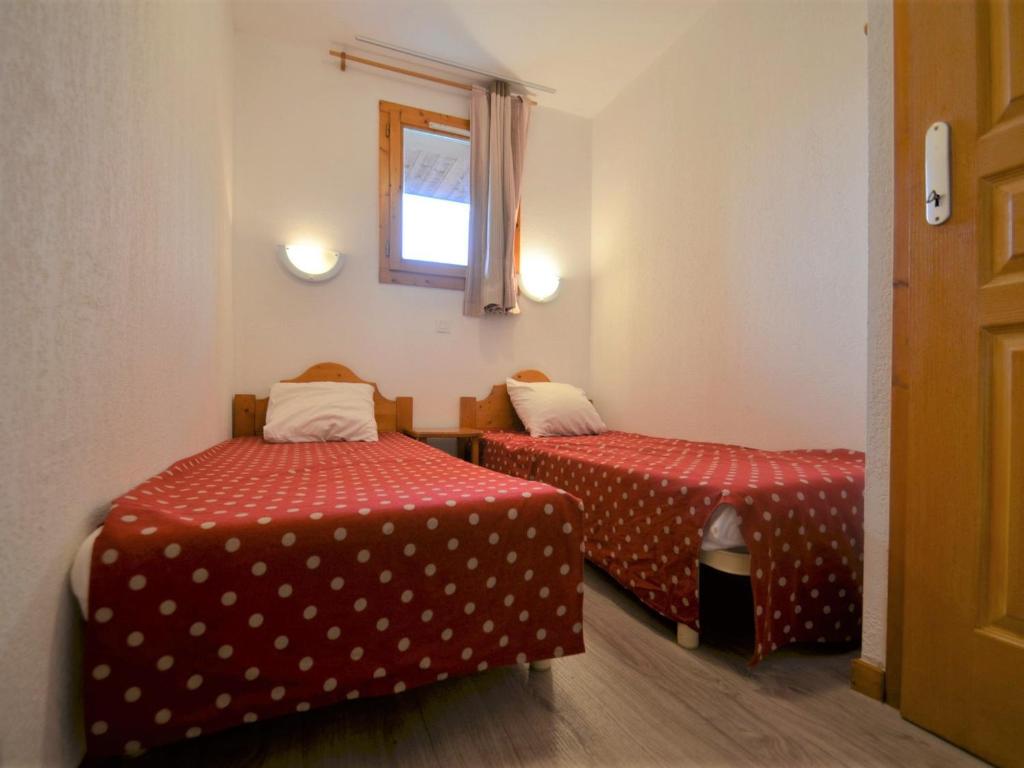a room with two beds with red sheets and a window at Appartement Les Menuires, 2 pièces, 4 personnes - FR-1-452-253 in Les Menuires