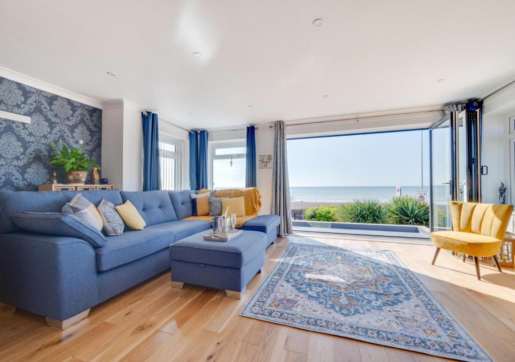 a living room with a blue couch and large windows at Vitamin Sea House in Worthing