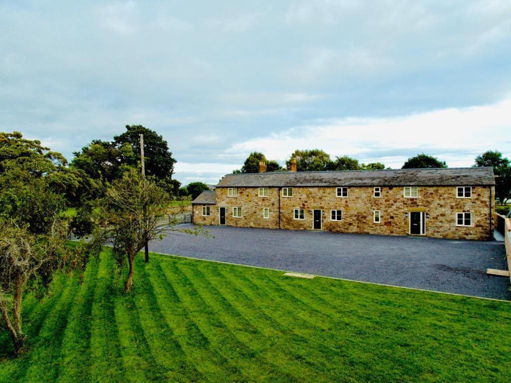 un ancien bâtiment en pierre avec un champ vert en face dans l'établissement Connah's Quay Park Farm Barns, à Connahs Quay