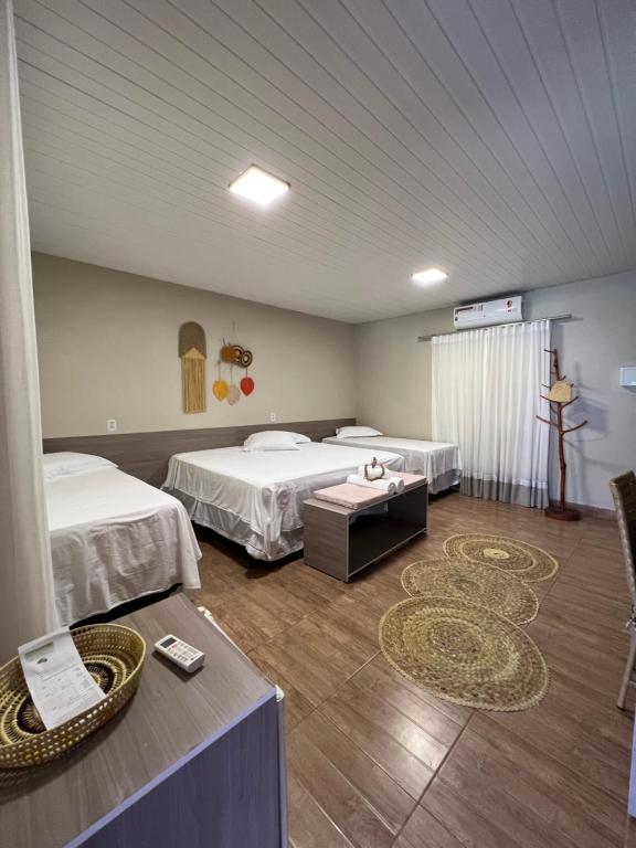 a hotel room with two beds and a table at Pousada do Lago Boutique in Santarém