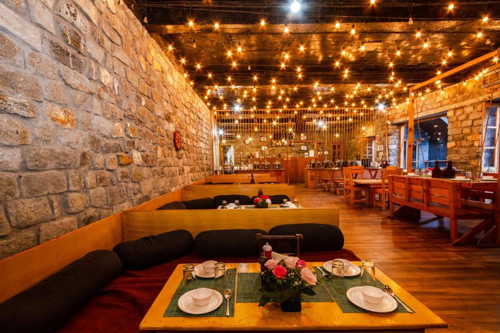 a dining room with a table and a brick wall at Winterfell The Stay, Unique River Front Resort in Manāli