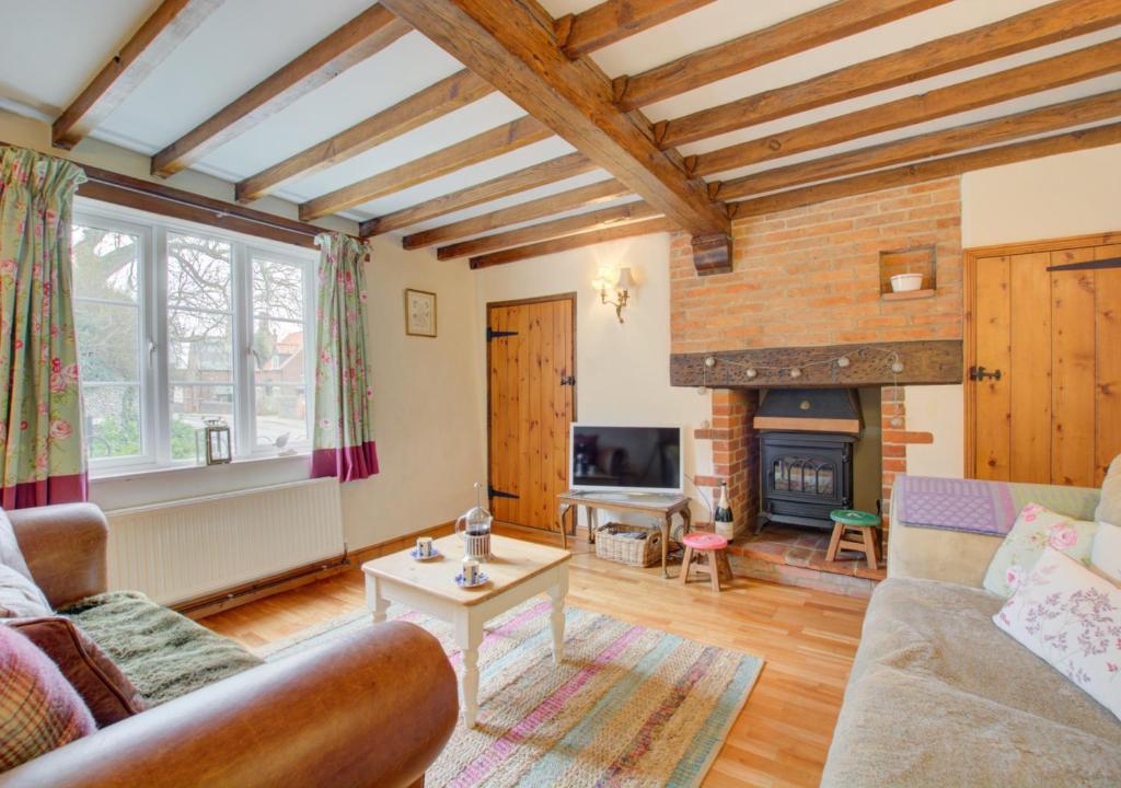 a living room with a couch and a fireplace at Camberley Cottage in Happisburgh