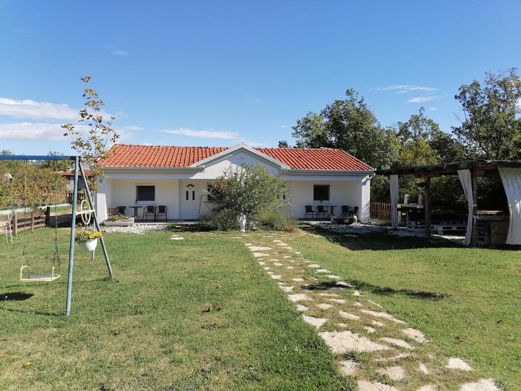 una casa con un patio con un columpio en Kristalni Slap Kravice en Ljubuški