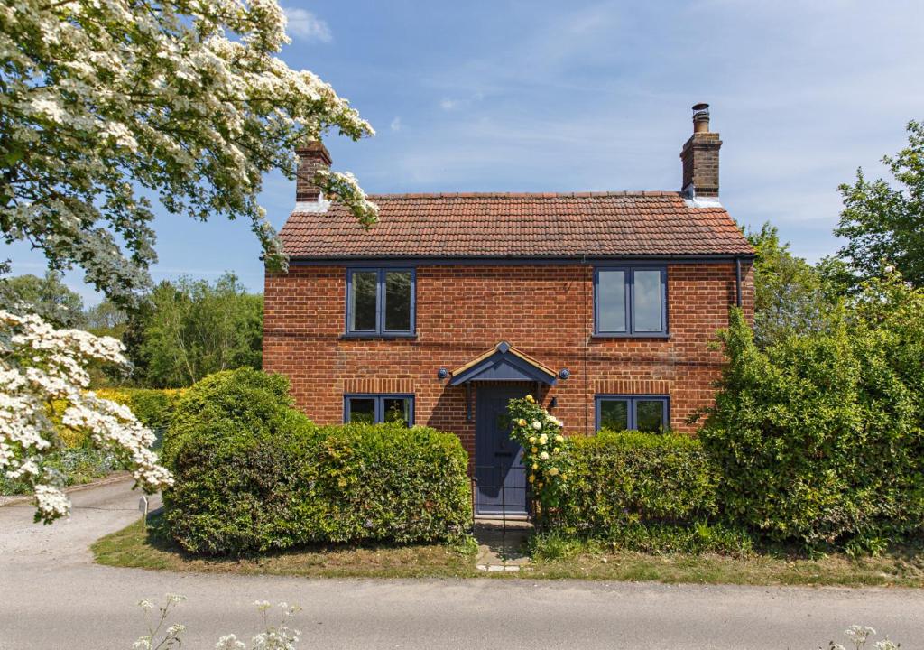a red brick house with bushes in front of it at The Cottage in Hickling