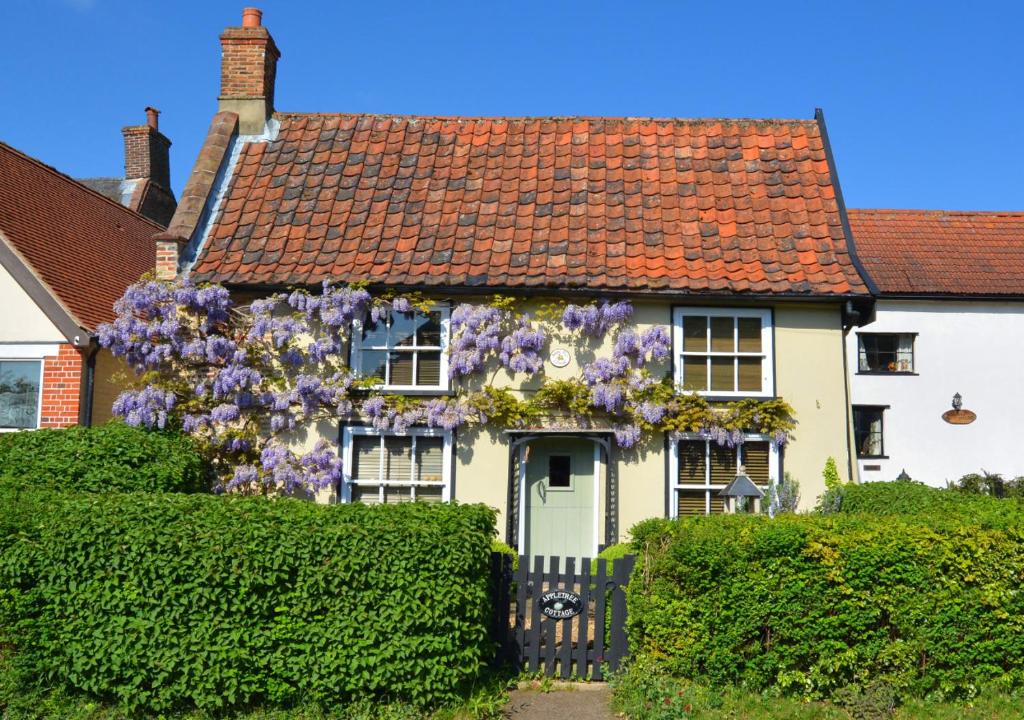 a house with a wreath of purple flowers on it at Apple Tree Cottage in Poringland