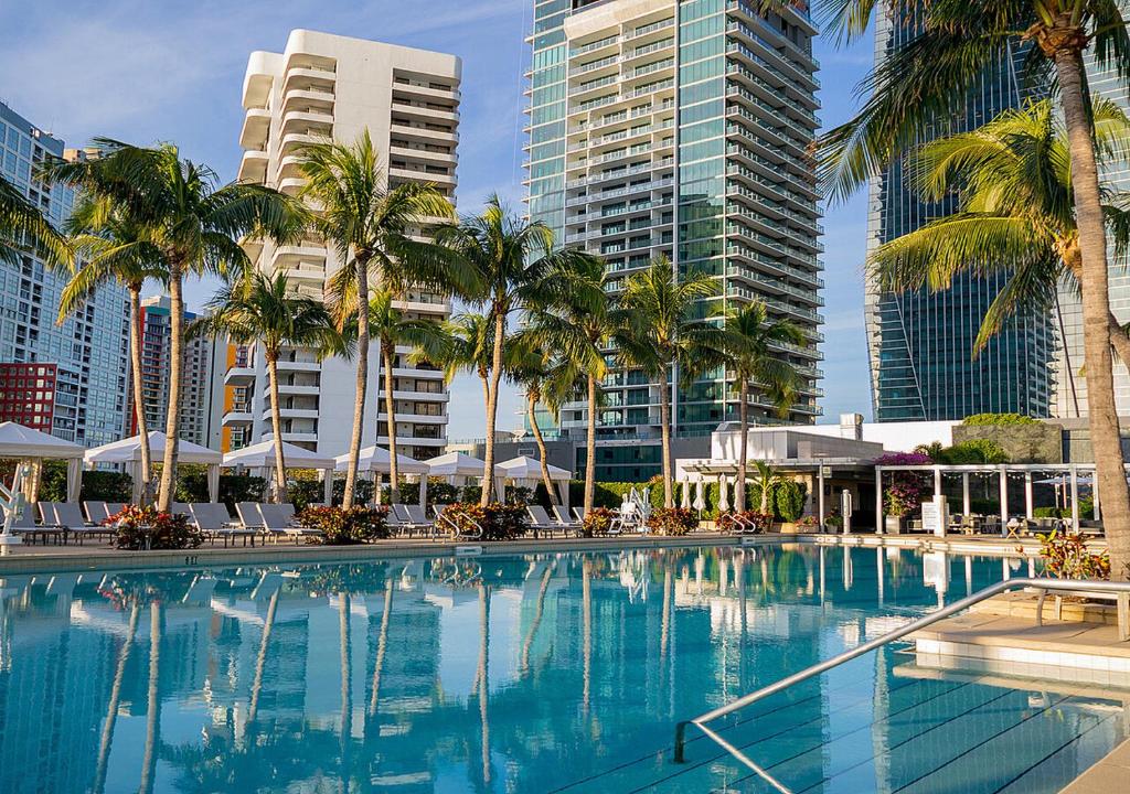 a large swimming pool with palm trees and buildings at Amazing studio in Four Seasons Residences Brickell! in Miami