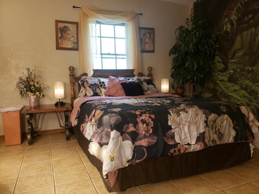 ein Schlafzimmer mit einem Bett mit einer Bettdecke und einem Fenster in der Unterkunft Cute Forest Themed Room With Kitchenette & Wifi in Mena