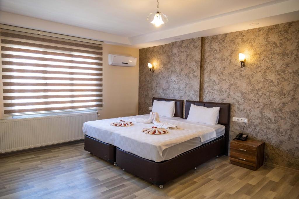 a bedroom with a large bed with towels on it at ikarushotel in Aydın