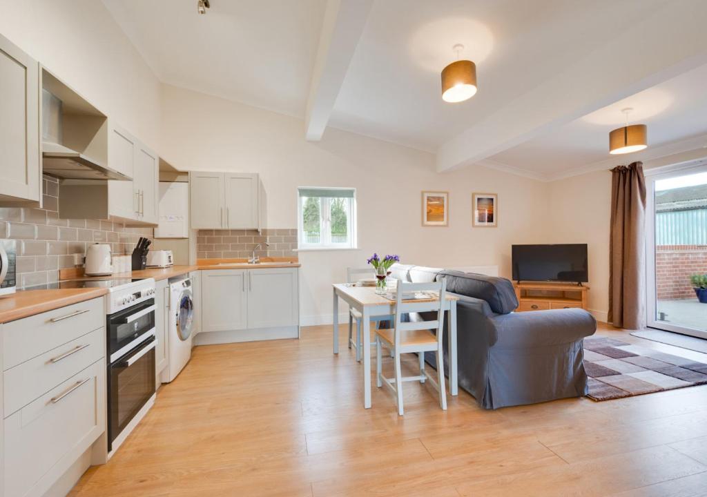 eine Küche und ein Wohnzimmer mit einem Tisch und einem Sofa in der Unterkunft The Workshop in Chedgrave