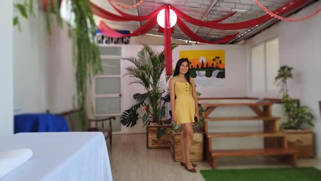 Una mujer con un vestido amarillo parada en una habitación en Villa Isai.Hospedaje Spa.., en Baños