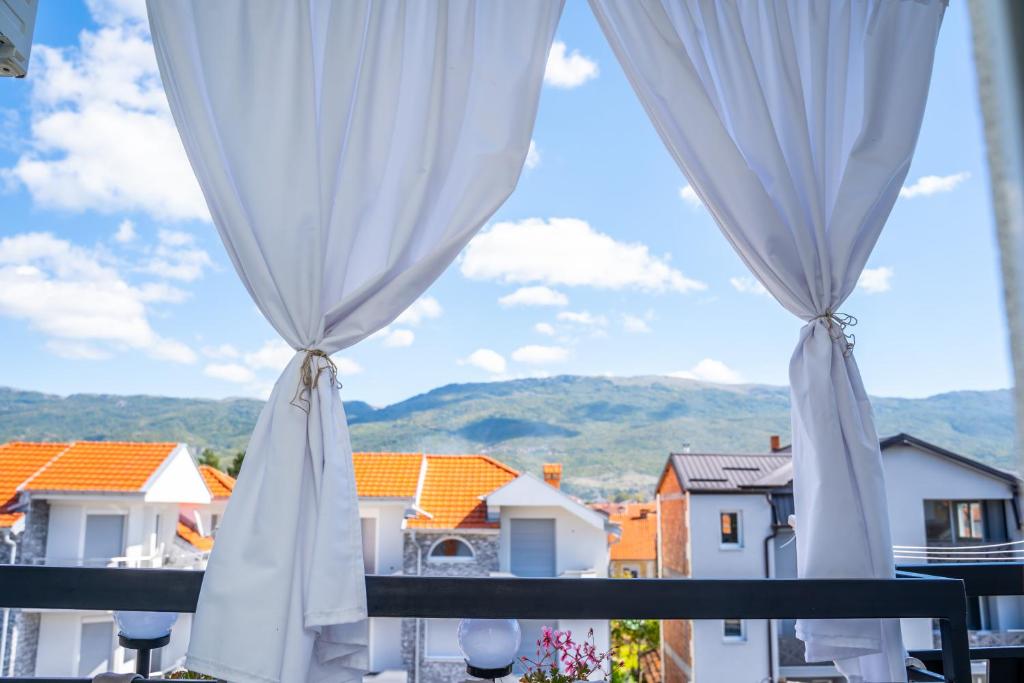 balcón con vistas a las casas y cortinas blancas en Finesi Apartments 2 en Ohrid