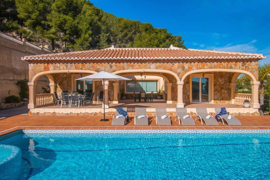 a villa with a swimming pool in front of a house at Villa Noa - PlusHolidays in Calpe