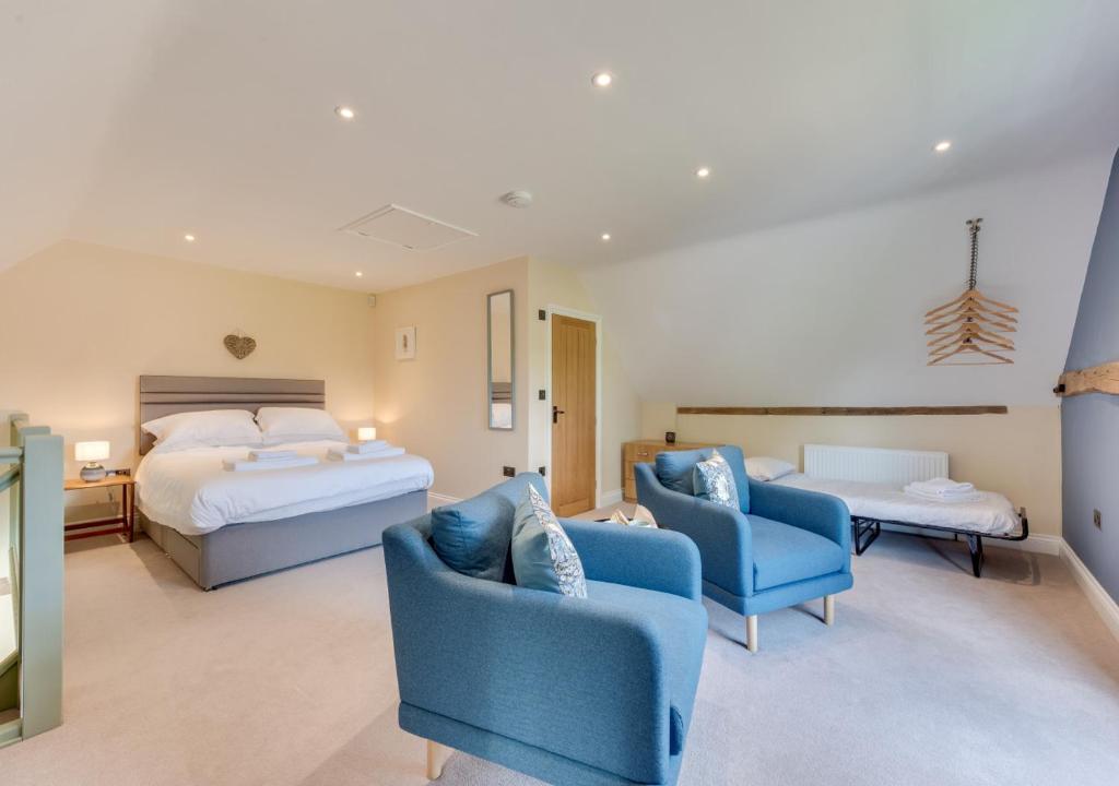 a bedroom with two beds and two blue chairs at The Cart Shed in Thurton