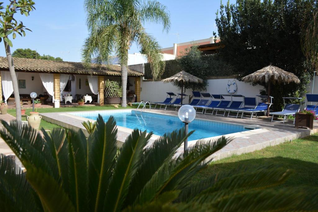 una piscina con sillas azules y una casa en Brunelli Residence, en Mazara del Vallo