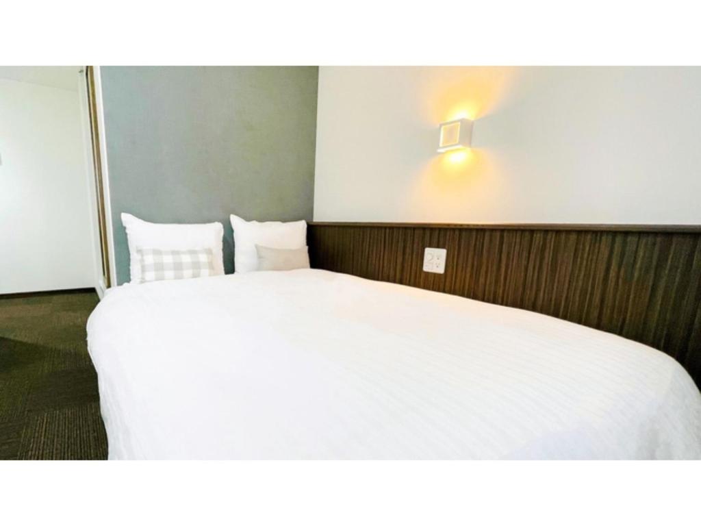 Eins,Inn Umeda Higashi - Vacation STAY 30031v في أوساكا: غرفة نوم بسرير ابيض واضاءة على الحائط