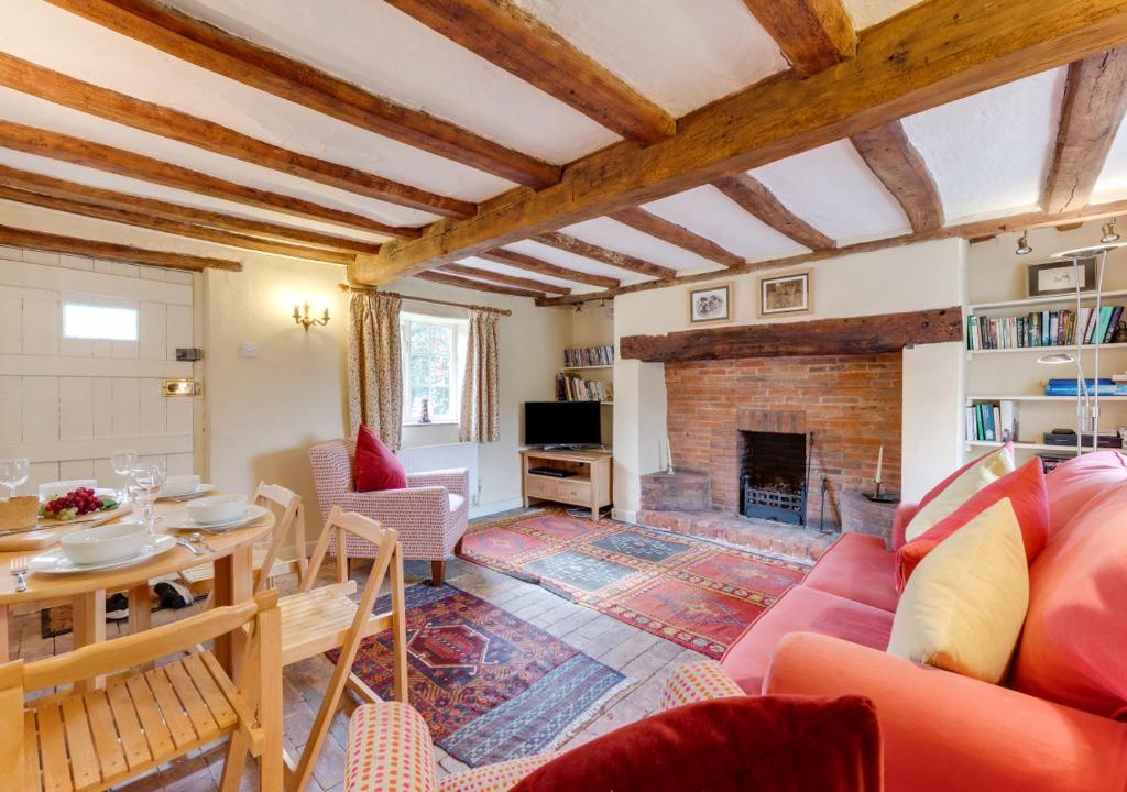 a living room with a table and a fireplace at Appletree Cottage in Westleton