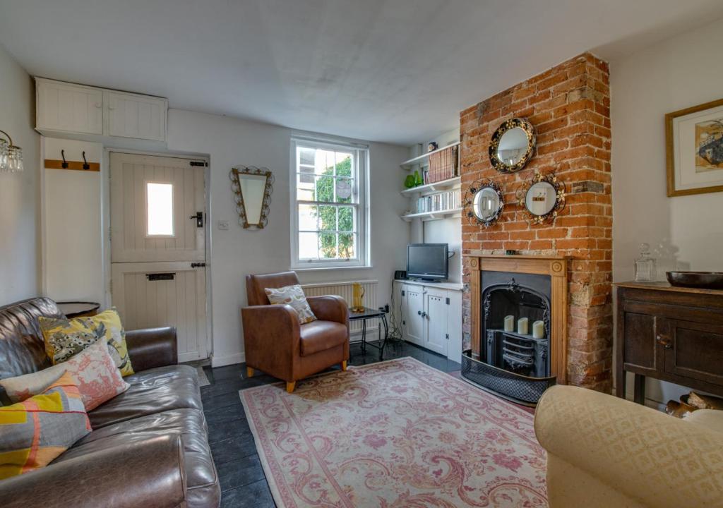 a living room with a couch and a brick fireplace at Jasmine Cottage in Woodbridge