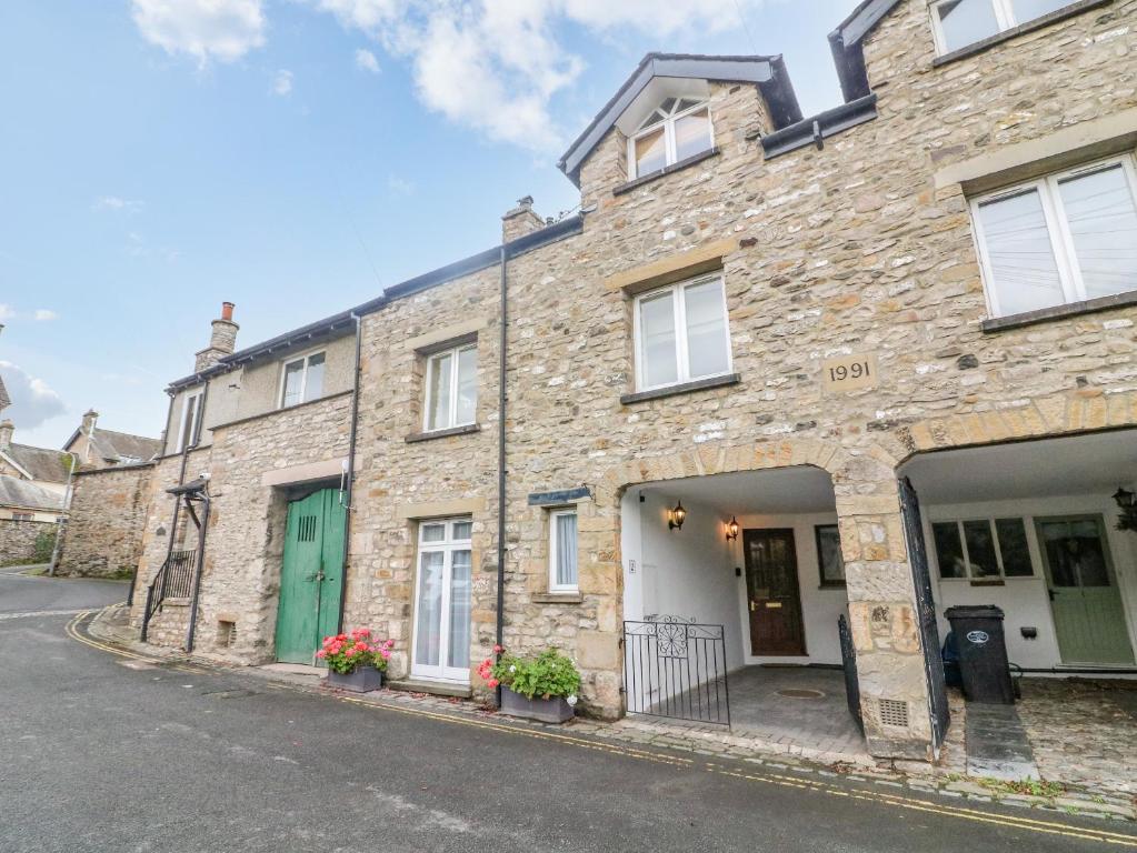 a stone house with a green door on a street at No 2 The Mews in Carnforth